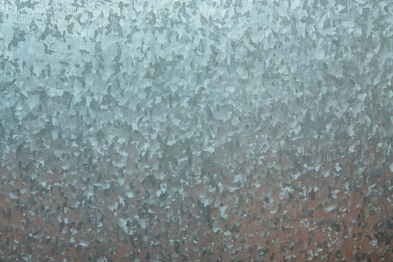 Gros plan sur une texture de tôle galvanisée (zinc), grain irrégulier bleu-gris